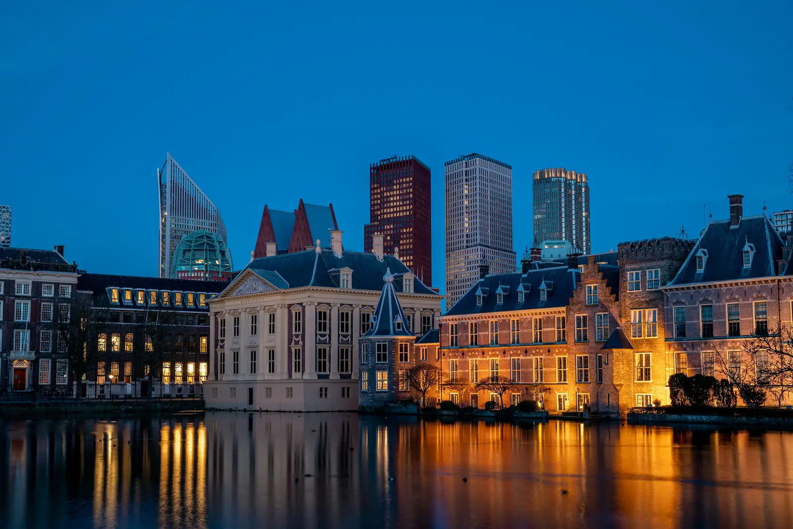 Binnenhof en Mauritshuis aan de Hofvijver in Den Haag tijdens het blauwe uur, met hoogbouw op de achtergrond