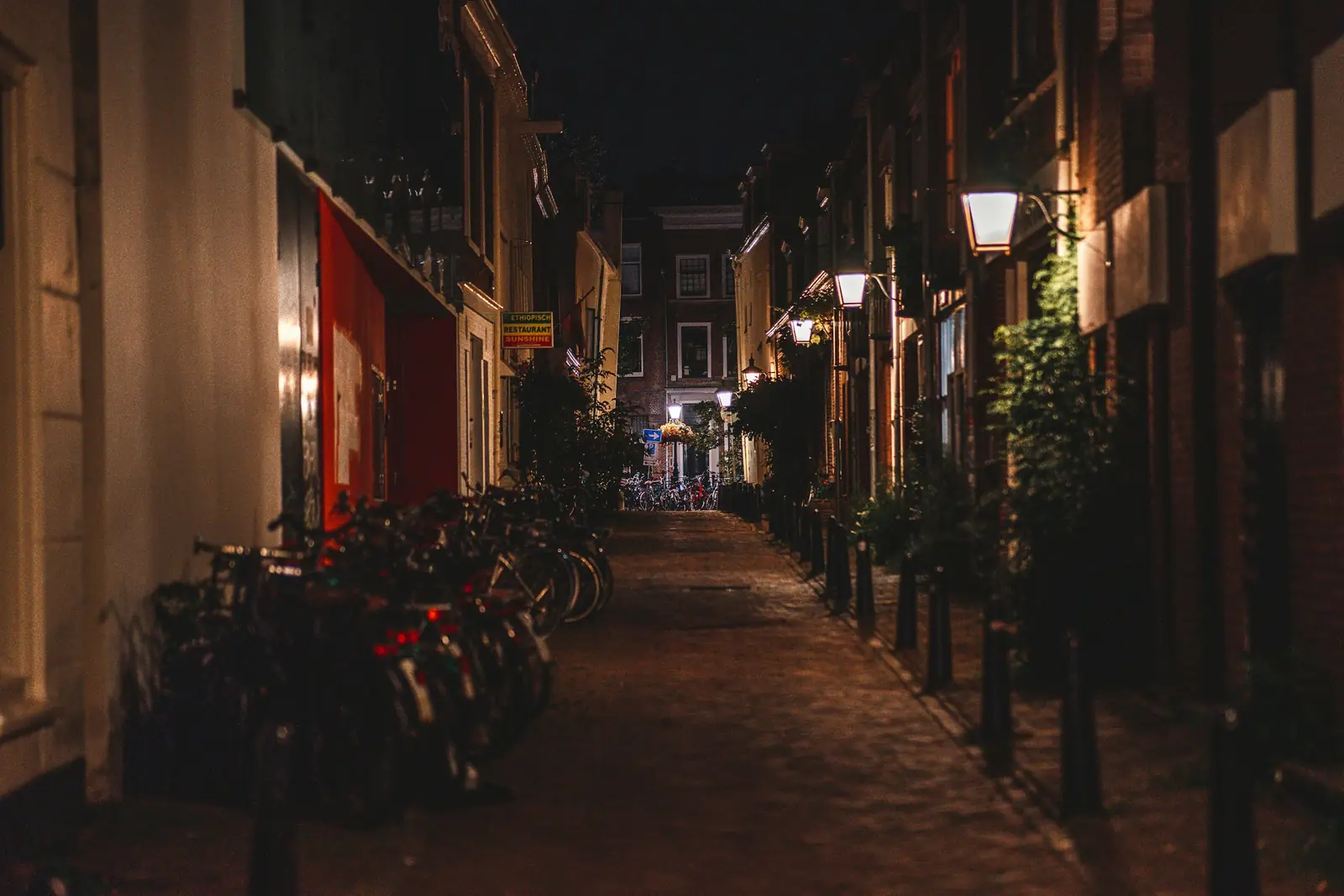 Smalle Nederlandse straat bij nacht met geparkeerde fietsen en verlichte gevels