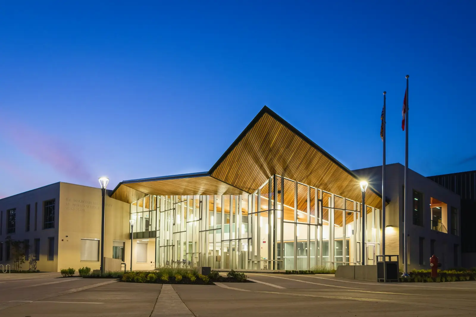 Leeg schoolgebouw met verlichte glazen entree tijdens het blauwe uur
