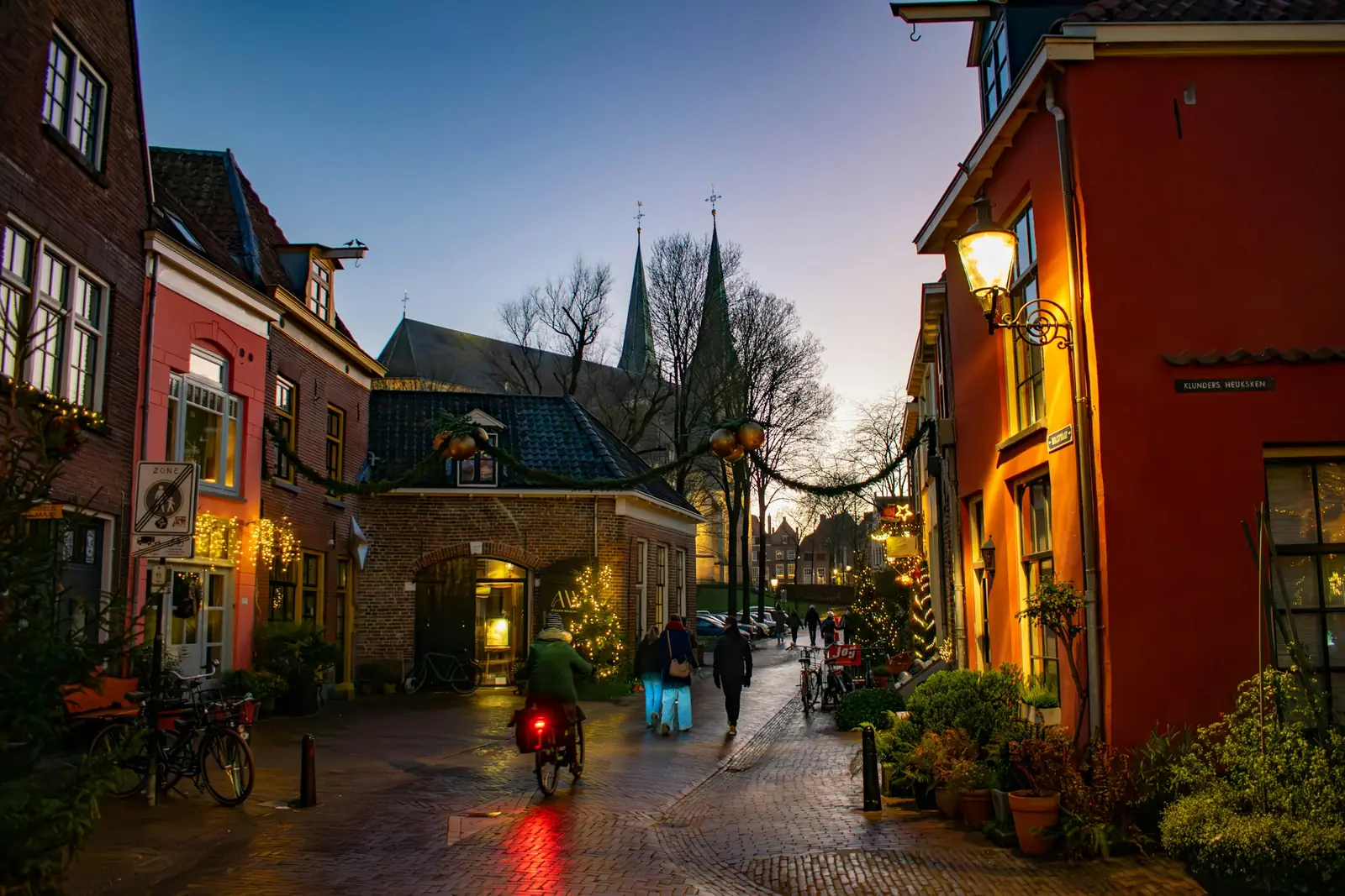 Winkelstraatje in Deventer in de schemering, met verlichte etalages, kerstversiering en een fietser